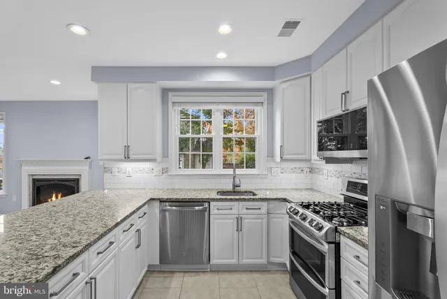 a kitchen with stainless steel appliances granite countertop a stove a sink dishwasher a refrigerator and a microwave