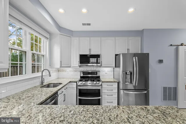 a kitchen with granite countertop a refrigerator stove and sink