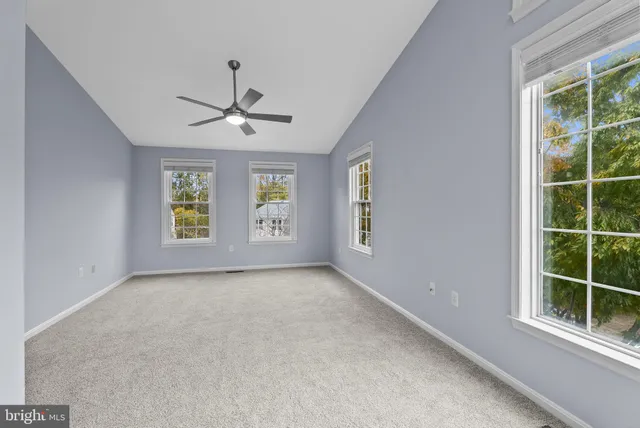 an empty room with windows and ceiling fan