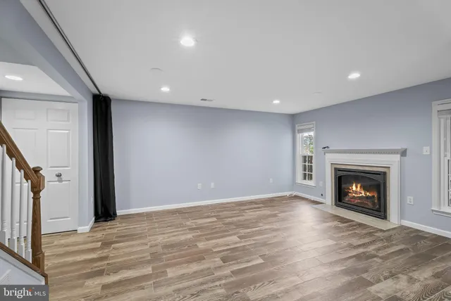 a view of an empty room with wooden floor fireplace and a window