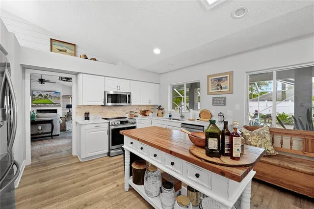 a kitchen with stainless steel appliances granite countertop a stove refrigerator and a dining table with wooden floor