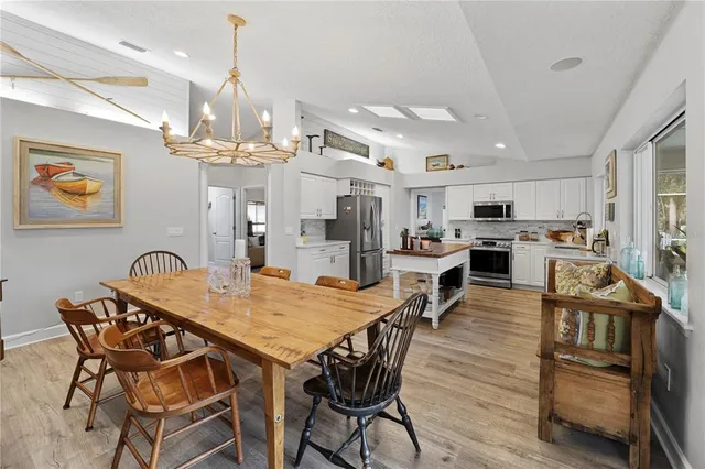 a view of a dining room and livingroom with furniture wooden floor a chandelier