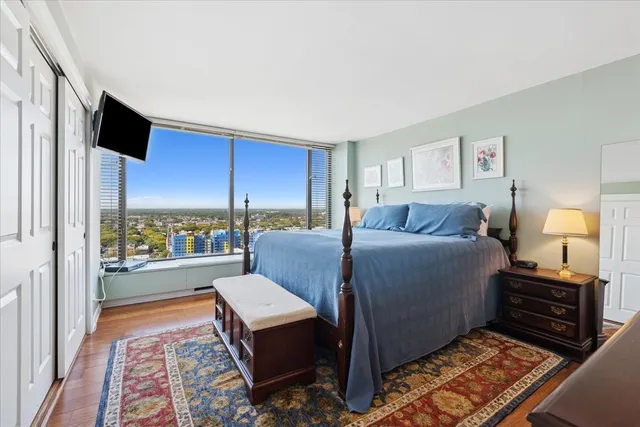 a living room with a bed furniture flat screen tv and a large window
