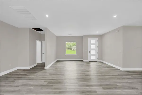 a view of an empty room with window and wooden floor
