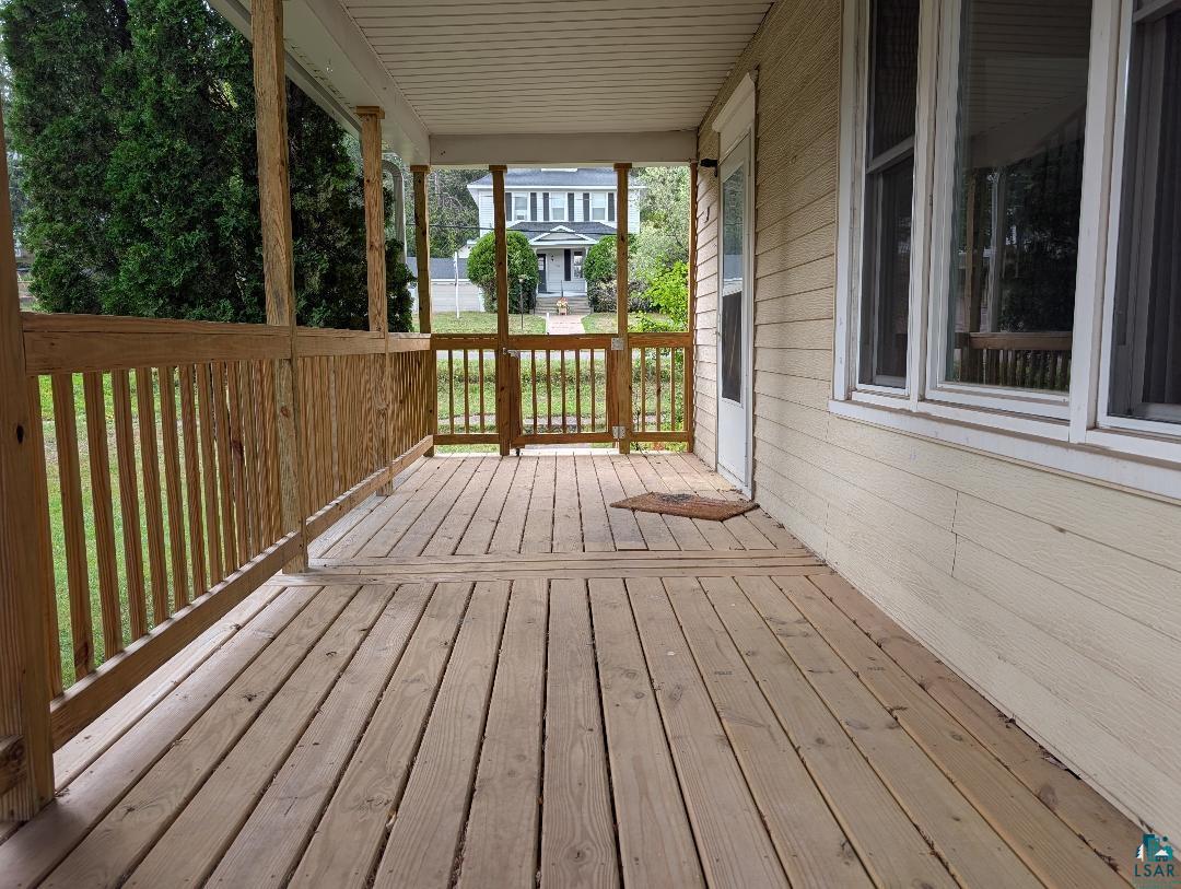 202 Thomas Street Mellen, WI 54546 - Photo 13 of 37 Expansive wooden front porch with a slatted railing, wooden support beams, and light-colored siding