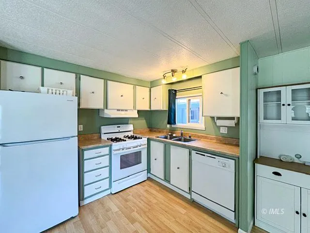 a kitchen with a sink a refrigerator and white cabinets