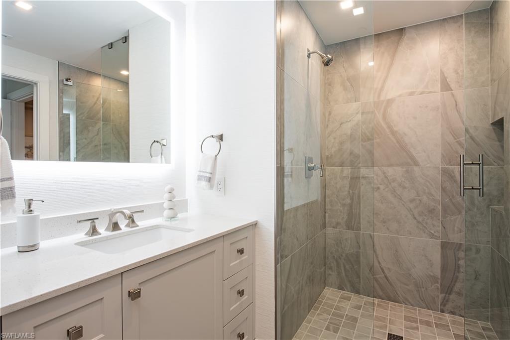 13915 Old Coast Road, Unit 602 Naples, FL 34110 - Photo 18 of 37 a bathroom with a shower sink vanity and mirror