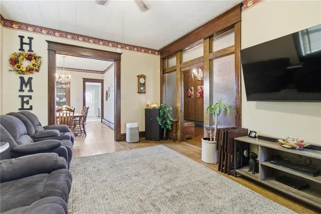 a living room with furniture a flat screen tv and floor to ceiling window