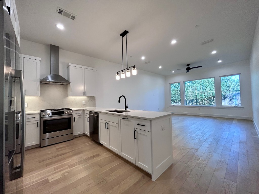 a large kitchen with granite countertop a stove top oven a sink a counter space and wooden floor