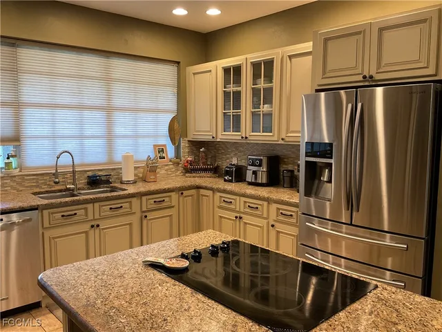 a kitchen with granite countertop a refrigerator stove sink and cabinets