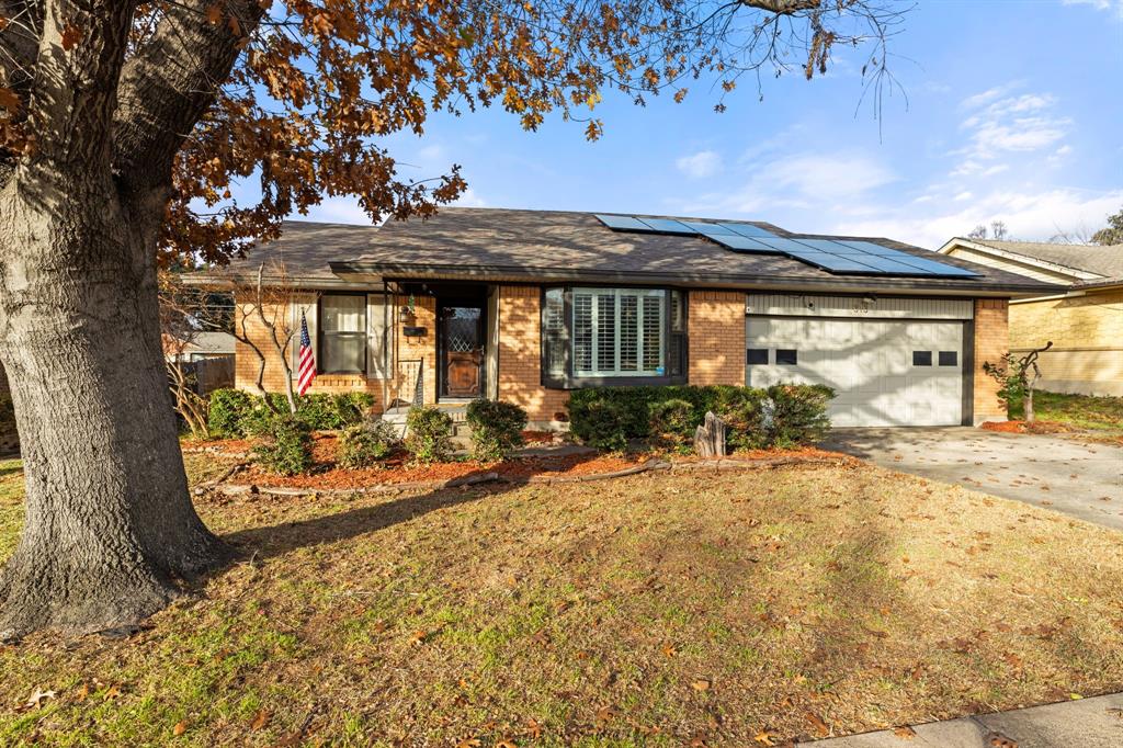 313 Stanton Drive Garland, TX 75042 - Photo 1 of 1 Ranch-style house with concrete driveway, a shingled roof, a garage, solar panels, and brick siding