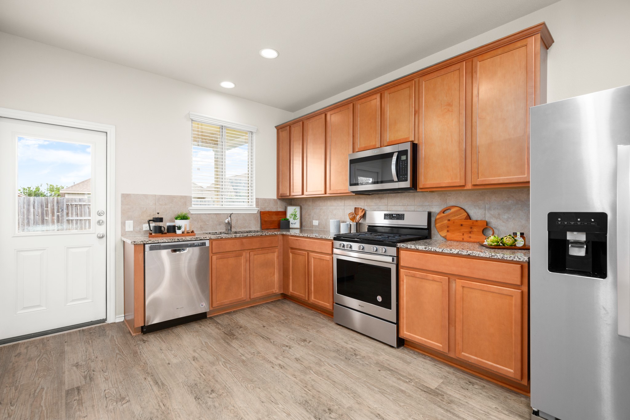 380 Bonnet Boulevard Georgetown, TX 78628 - Photo 4 of 26 a kitchen with stainless steel appliances granite countertop a stove top oven a sink dishwasher and a refrigerator with wooden floor