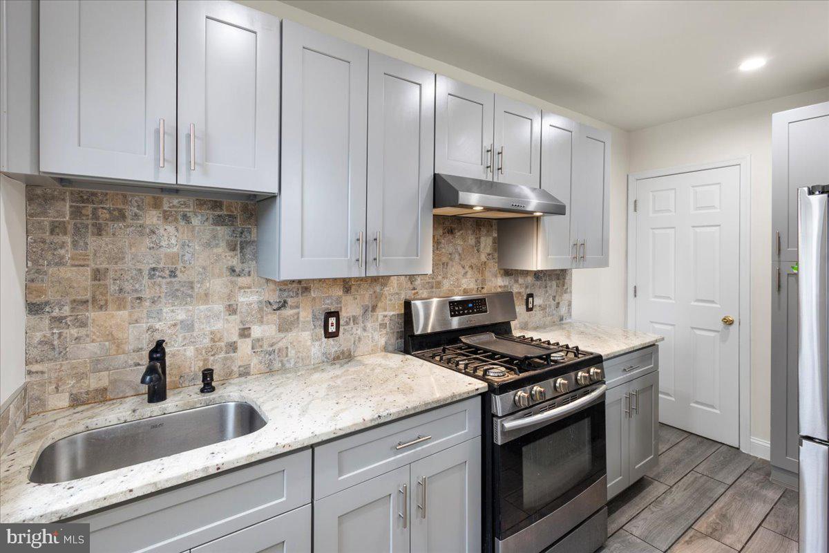 4027 D Street Southeast Washington, DC 20019 - Photo 13 of 32 a kitchen with granite countertop a sink a stove and cabinets