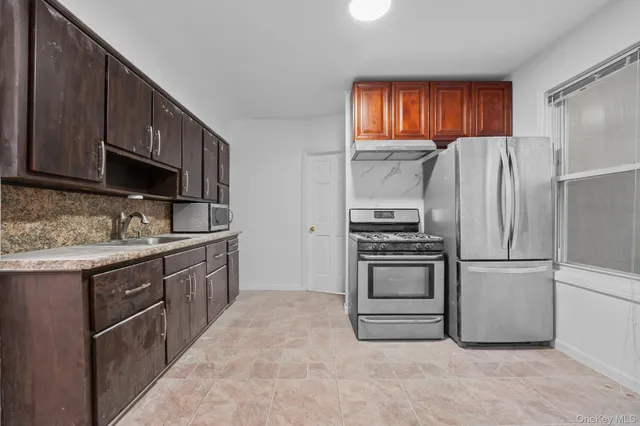 a kitchen with granite countertop a refrigerator stove and sink