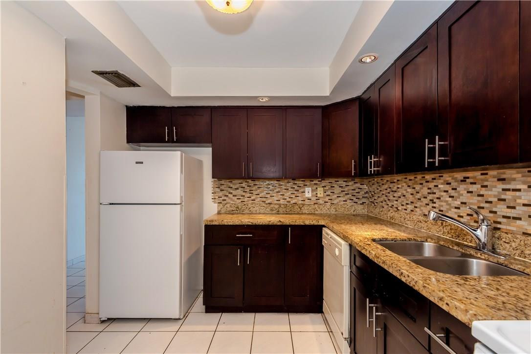 3285 Foxcroft Road, Unit E317 Miramar, FL 33025 - Photo 11 of 28 a kitchen with a sink and a refrigerator