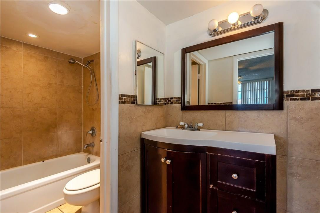 3285 Foxcroft Road, Unit E317 Miramar, FL 33025 - Photo 17 of 28 a bathroom with a bathtub shower sink vanity and toilet