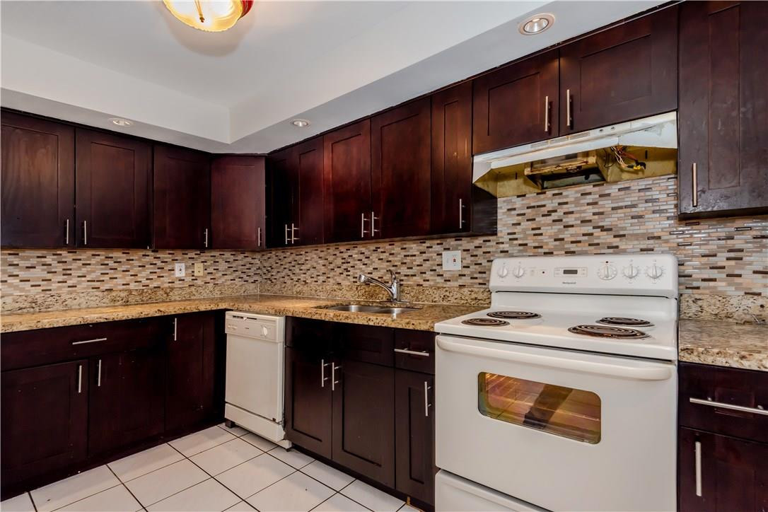 3285 Foxcroft Road, Unit E317 Miramar, FL 33025 - Photo 10 of 28 a kitchen with granite countertop wooden cabinets and a stove top oven
