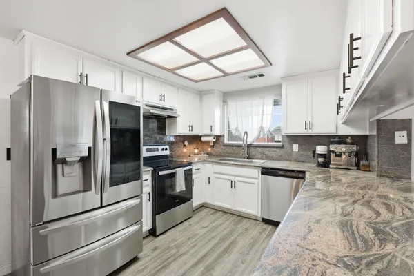 a kitchen with stainless steel appliances granite countertop a refrigerator a stove and a sink