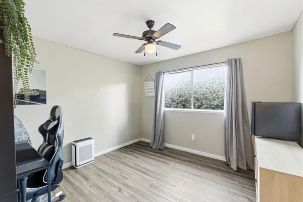 a view of an empty room with a window and wooden floor