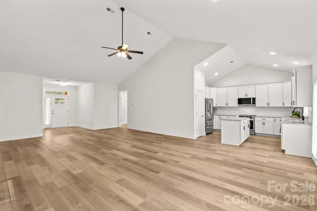 a view of a kitchen with kitchen island wooden floor center island and stainless steel appliances