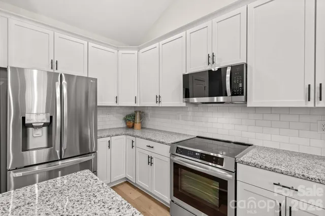 a kitchen with stainless steel appliances granite countertop a refrigerator stove and sink
