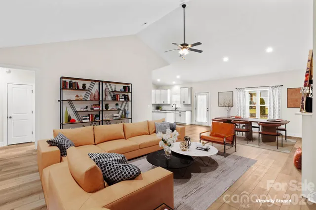 a living room with furniture kitchen view and a wooden floor