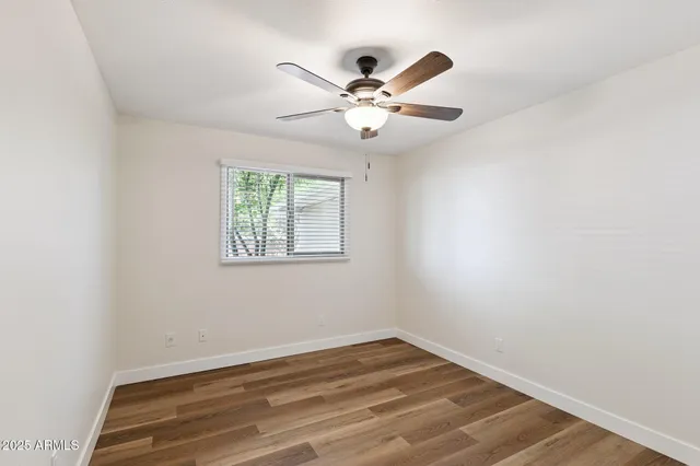 an empty room with wooden floor fan and windows