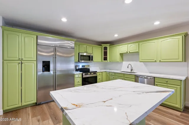 a kitchen with stainless steel appliances kitchen island a refrigerator sink and cabinets