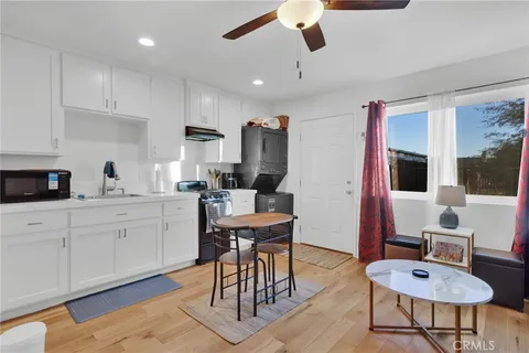 a open kitchen with stainless steel appliances granite countertop a stove a sink dishwasher a dining table and chairs with wooden floor