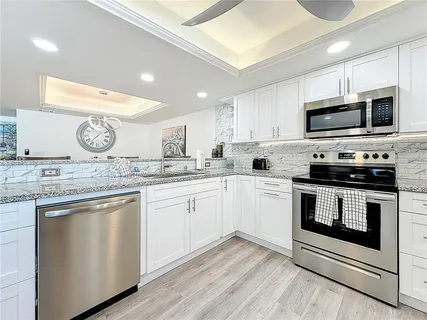 a kitchen with kitchen island granite countertop a sink appliances cabinets and a counter space