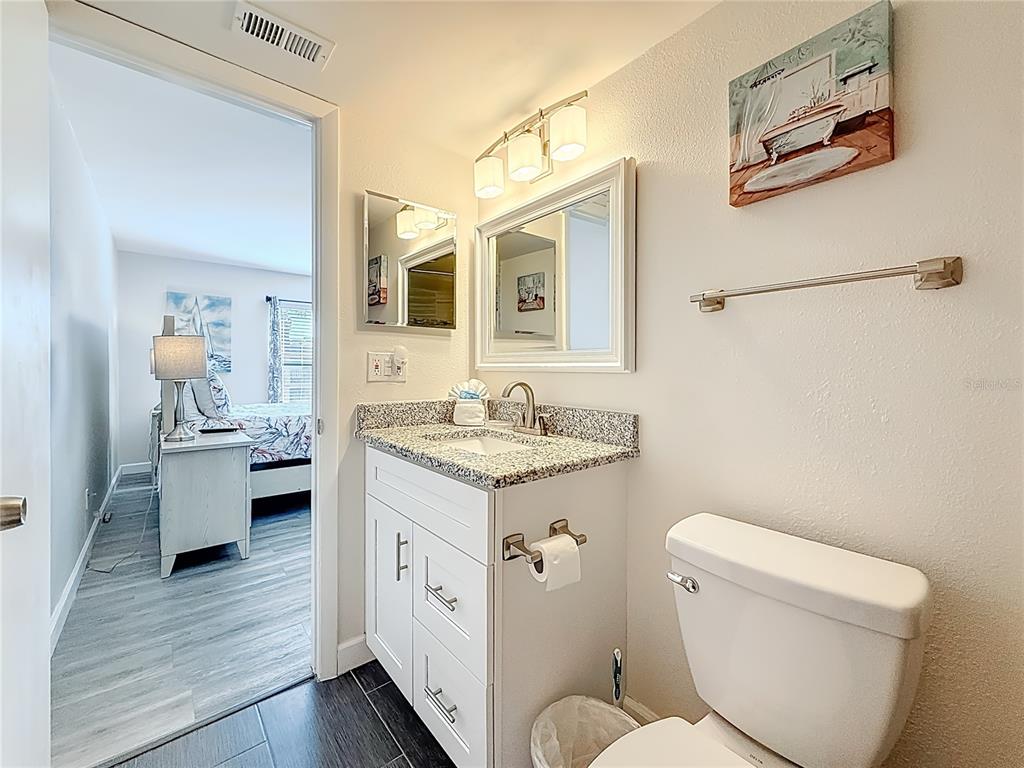 19725 Gulf Boulevard, Unit 46 Indian Rocks Beach, FL 33785 - Photo 30 of 55 a bathroom with a granite countertop toilet sink and mirror