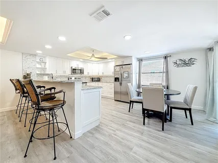 a kitchen with stainless steel appliances kitchen island granite countertop a table chairs and a refrigerator