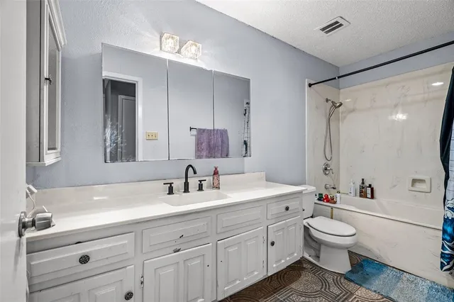 a bathroom with a toilet a sink a mirror a shower a vanity and window