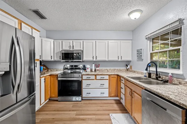 a kitchen with stainless steel appliances granite countertop a stove a sink dishwasher a refrigerator and a microwave oven