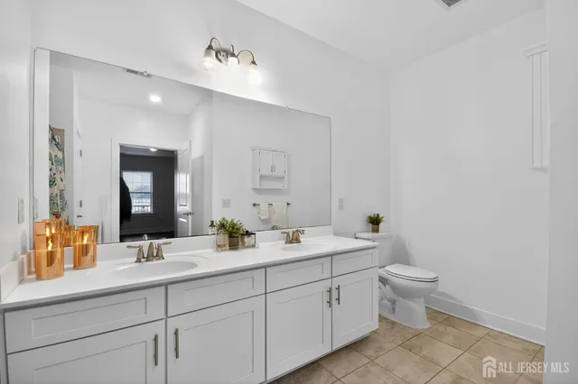 a spacious bathroom with a double vanity sink toilet and mirror