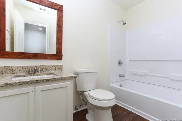 a bathroom with a granite countertop toilet sink and mirror