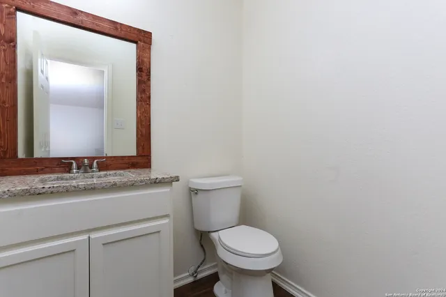 a bathroom with a granite countertop toilet and a sink