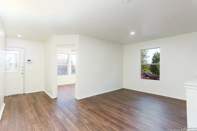 a view of an empty room with wooden floor and a window