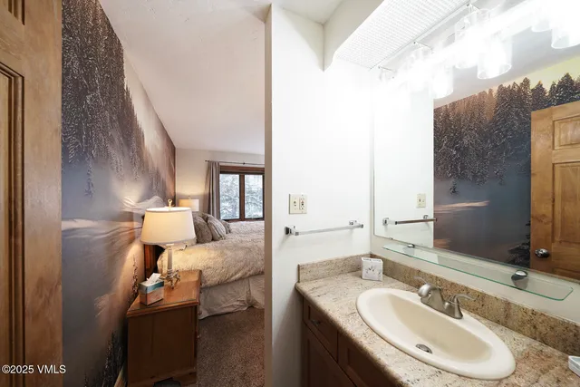 a en suite bathroom with a granite countertop sink and a mirror