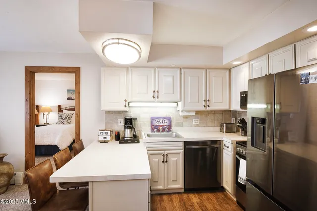 a kitchen with a sink dishwasher a refrigerator a stove and white cabinets with wooden floor