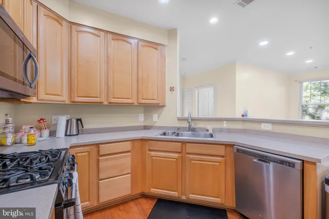 a kitchen with stainless steel appliances granite countertop a sink and cabinets with wooden floor
