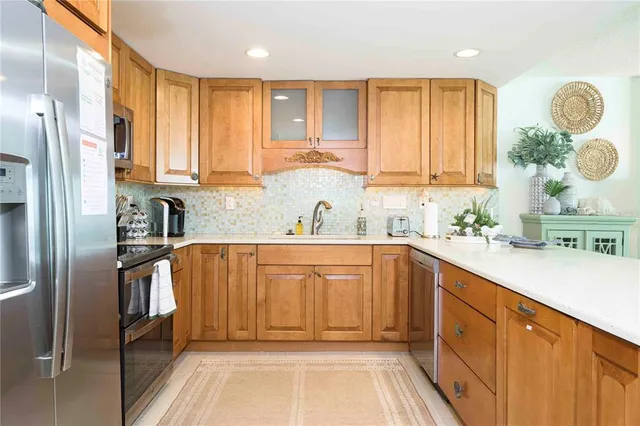 a kitchen with stainless steel appliances kitchen island granite countertop a sink and refrigerator