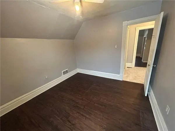 an empty room with wooden floor and mirror
