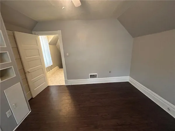a view of a hallway with wooden floor and a bathroom