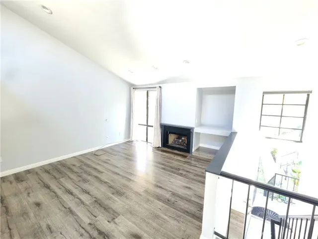 a view of an empty room and wooden floor with fireplace
