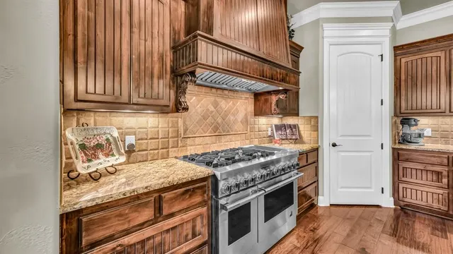a kitchen with stainless steel appliances granite countertop a sink a stove and a wooden floors
