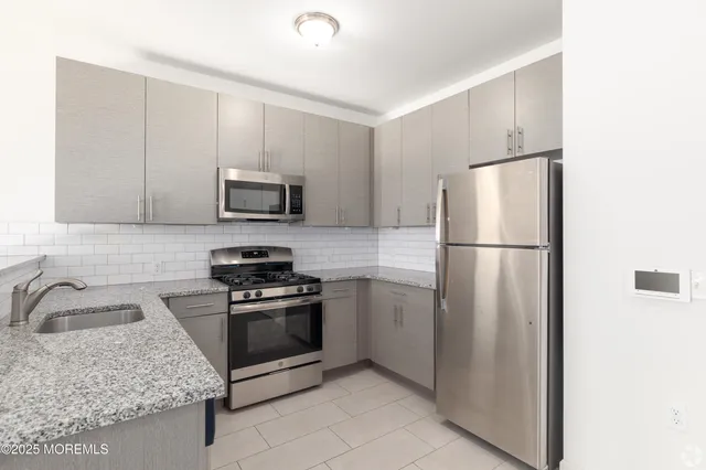 a kitchen with granite countertop a refrigerator and a sink