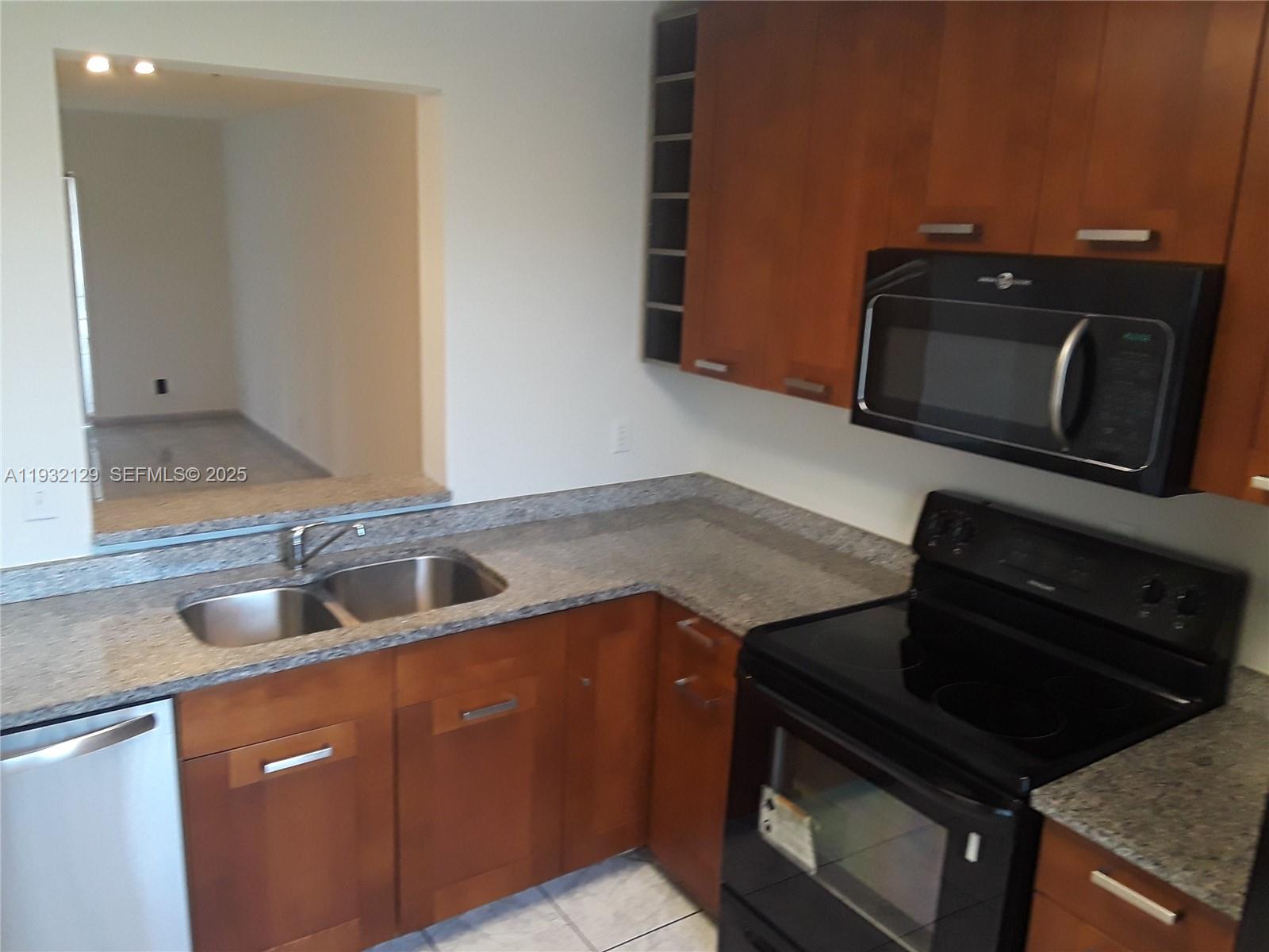 8700 Sherman Circle North, Unit 407 Miramar, FL 33025 - Photo 2 of 12 a kitchen with granite countertop a stove and a microwave