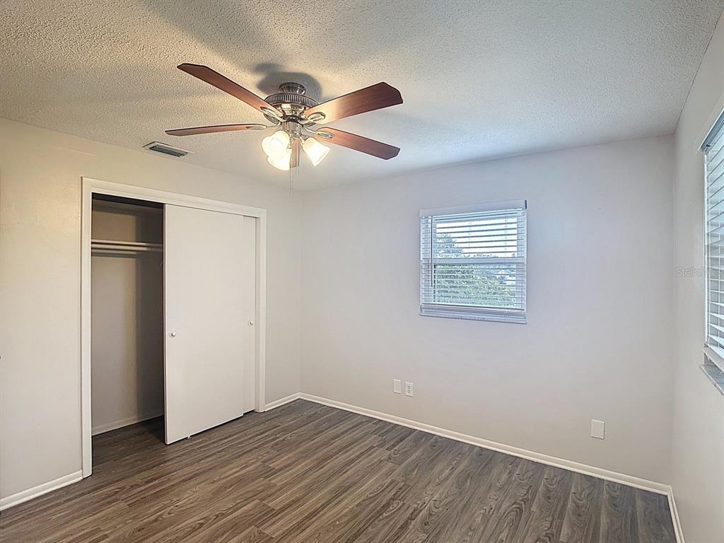 11320 Currie Lane Largo, FL 33774 - Photo 12 of 40 a view of an empty room with wooden floor and a ceiling fan