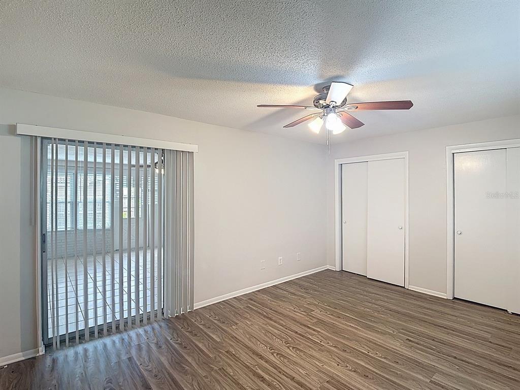 11320 Currie Lane Largo, FL 33774 - Photo 19 of 40 a view of an empty room with wooden floor and a ceiling fan